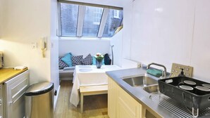 A compact kitchen with a window, a sink, a stove, and a trash bin. - Magical & Charming 8 rooms Covent Garden TownHouse (London)