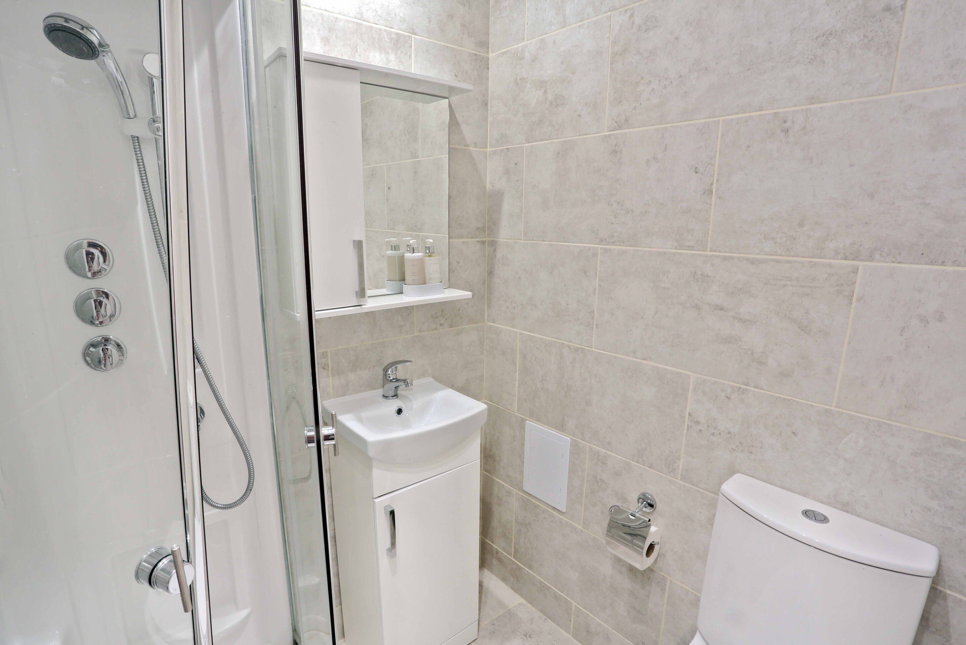 A modern bathroom with a glass-enclosed shower, a white sink, and a toilet.