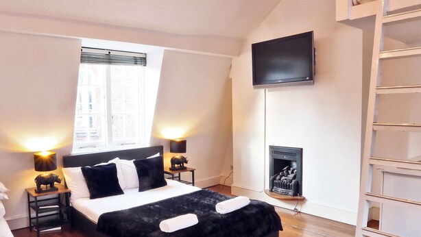 A bedroom with a bed, bedside lamps, a TV, a fireplace, and a loft bed. - Magical & Charming 8 rooms Covent Garden TownHouse (London)