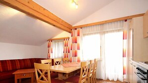 Ein Essbereich mit Holztisch und Stühlen, einer Couch und einer Küche mit Herd.