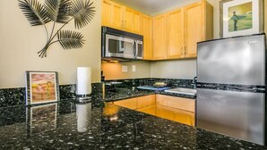 A kitchen with granite countertops, stainless steel appliances, wooden cabinets, and a decorative wall piece. - @ Marbella Lane - Mountain View Studio (Honolulu)
