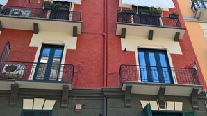 Ein Gebäude mit Balkonen, Fenstern und einer roten Fassade.