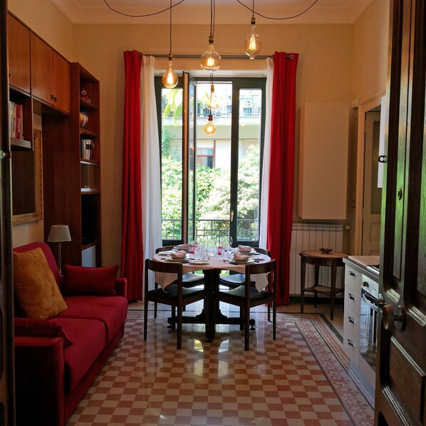 Un comedor con piso a cuadros, una mesa redonda preparada para cuatro personas y vistas a zonas verdes al exterior.