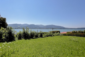 Un campo cubierto de hierba con un lago y montañas al fondo.