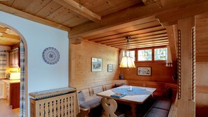 Un interior de fusta amb una zona d'asseients amb bancs, una taula i una làmpada penjant.
