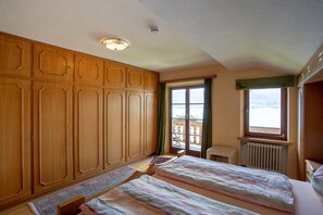 Un dormitorio con un armario grande, una cama con colcha, una ventana con vistas y un radiador.
