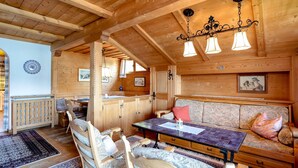 Un interior de fusta amb taula de menjador, cadires, un sofà i un llum penjant.