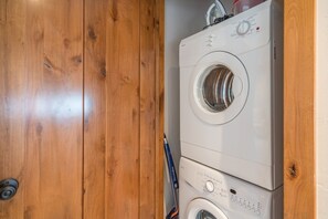 A front-loading washing machine and dryer stacked in a wooden closet.