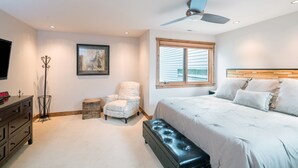 Une chambre à coucher comprenant un lit, une chaise, une commode, un ventilateur de plafond et une fenêtre.