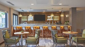 A bar area with wicker chairs, a bar counter, and a television screen. - Residence Inn by Marriott Oahu Kapolei (Kapolei)