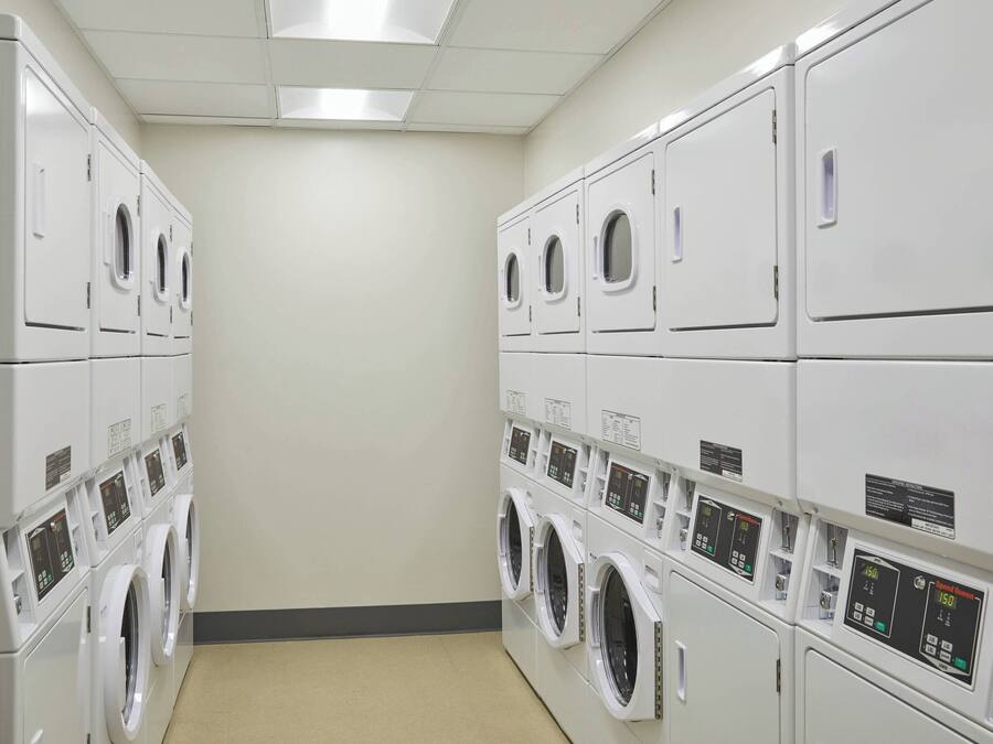 A laundry facility with multiple rows of stacked washing machines.