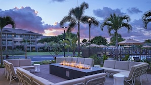 An outdoor seating area with a fire feature, wicker furniture, and a view of a building in the background. - Residence Inn by Marriott Oahu Kapolei (Kapolei)