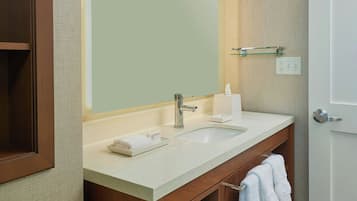 A bathroom with a large mirror, a sink, a towel rack, and a wooden cabinet.