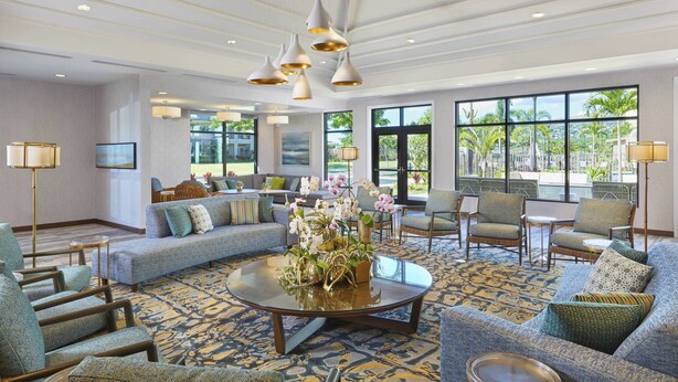 A spacious lobby with a round coffee table, sofas, and chairs arranged around a central area. Large windows provide a view of the outdoors. - Residence Inn by Marriott Oahu Kapolei (Kapolei)