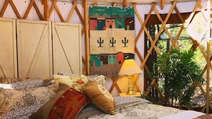 A cozy tented room with a bed, a lamp, and a wall hanging. - The YOGA YURTA... Extremely Civilized Glamping at SUNNY MELLOW ECO VILLA! (Village of Tijeras)