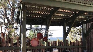 An outdoor kitchen with a wooden counter, stools, and various cooking appliances. - The YOGA YURTA... Extremely Civilized Glamping at SUNNY MELLOW ECO VILLA! (Village of Tijeras)