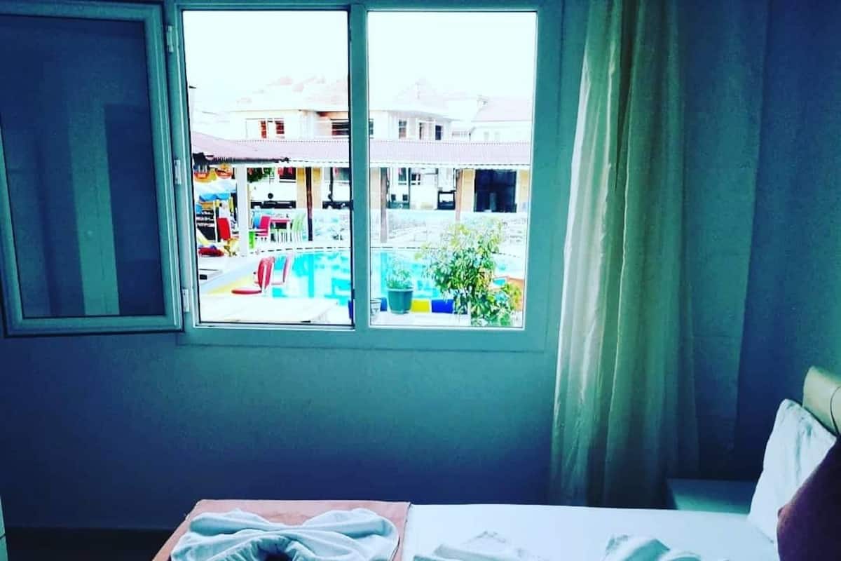 A hotel room with a bed, a window with a view of the street, and a table with towels.