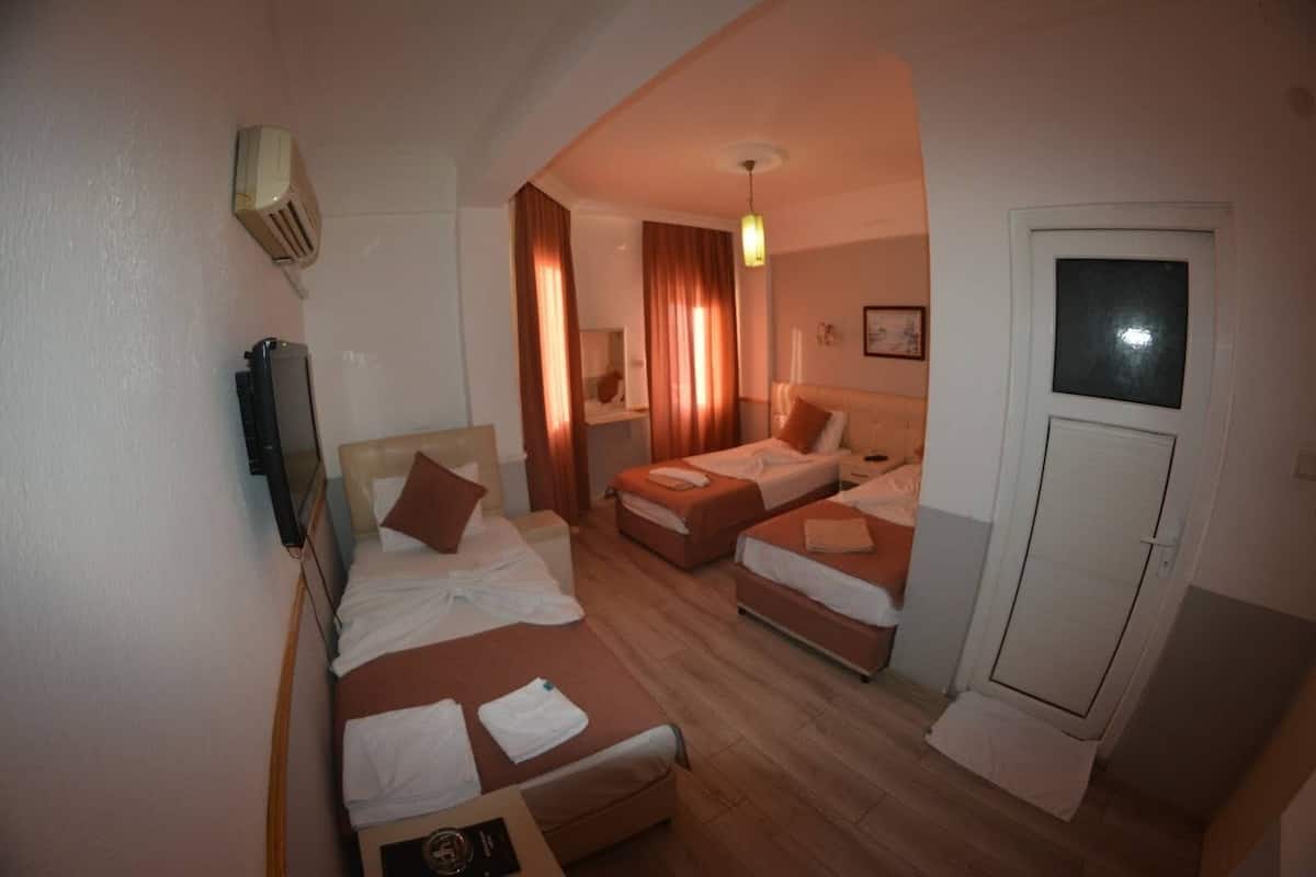 A hotel room with two beds, a desk, a chair, a TV, and a door.
