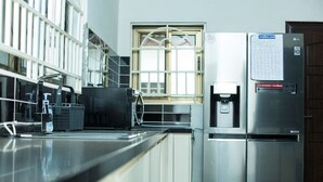 A modern kitchen with stainless steel appliances, a water dispenser, and a calendar on the fridge. - Beautiful Secure Home With 24 hour Security (Accra)