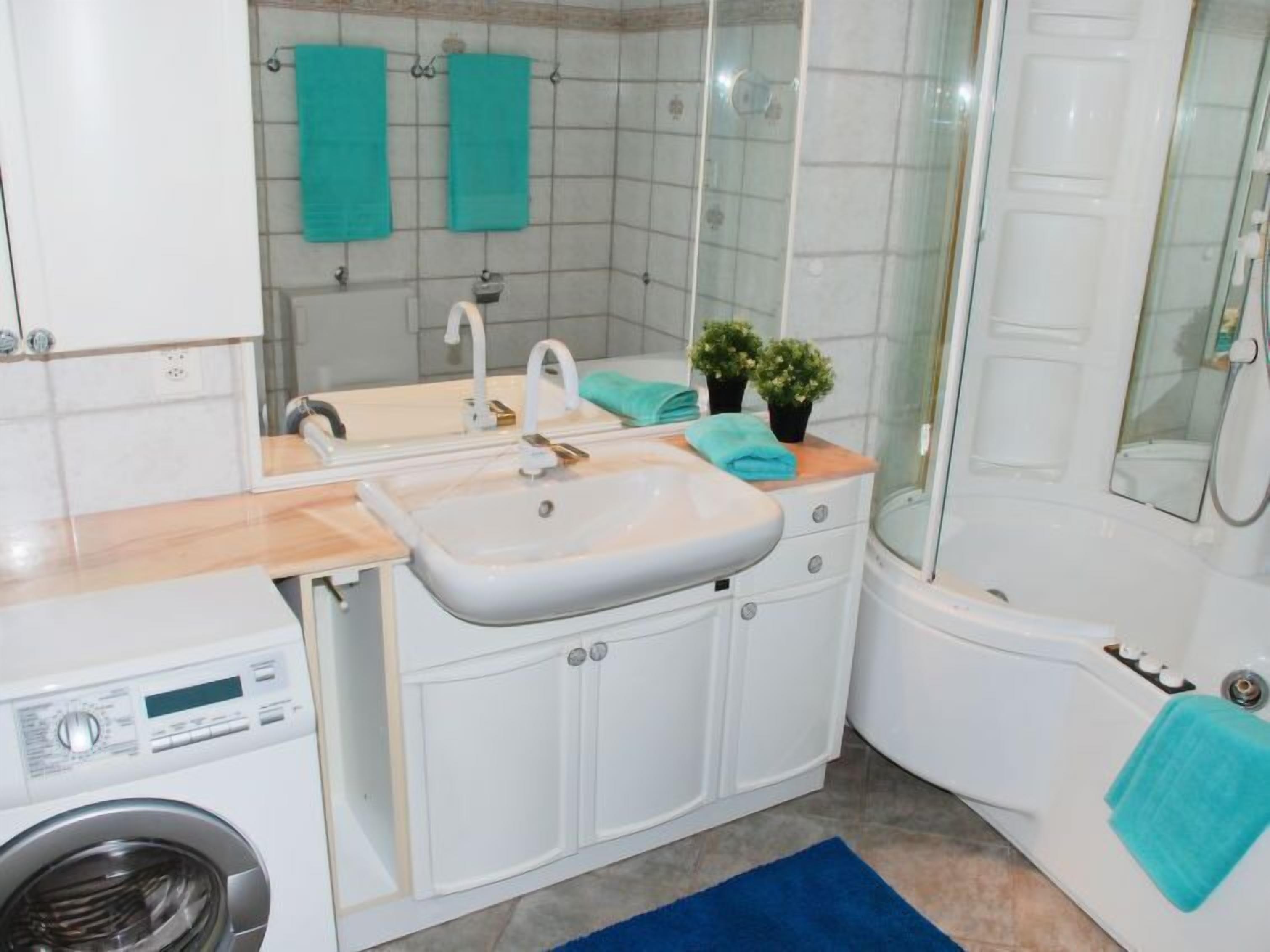 Un baño moderno con lavamanos, espejo y lavadora integrada.