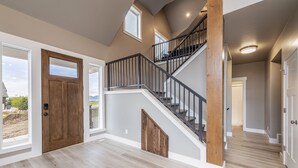 A spacious interior with a wooden staircase, large windows, and a view of the outdoors. - Foxridge (Sleeps 34) by Bear Lake Luxury Rentals (Garden City)
