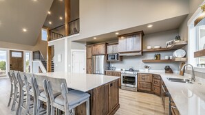 A spacious kitchen with a large island, wooden cabinets, and modern appliances. - Foxridge (Sleeps 34) by Bear Lake Luxury Rentals (Garden City)