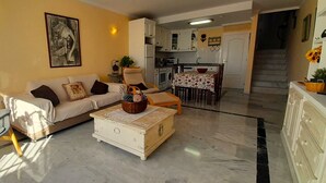 Uma sala de estar com sofá, mesa de centro e um espaço de jantar com mesa e cadeiras.