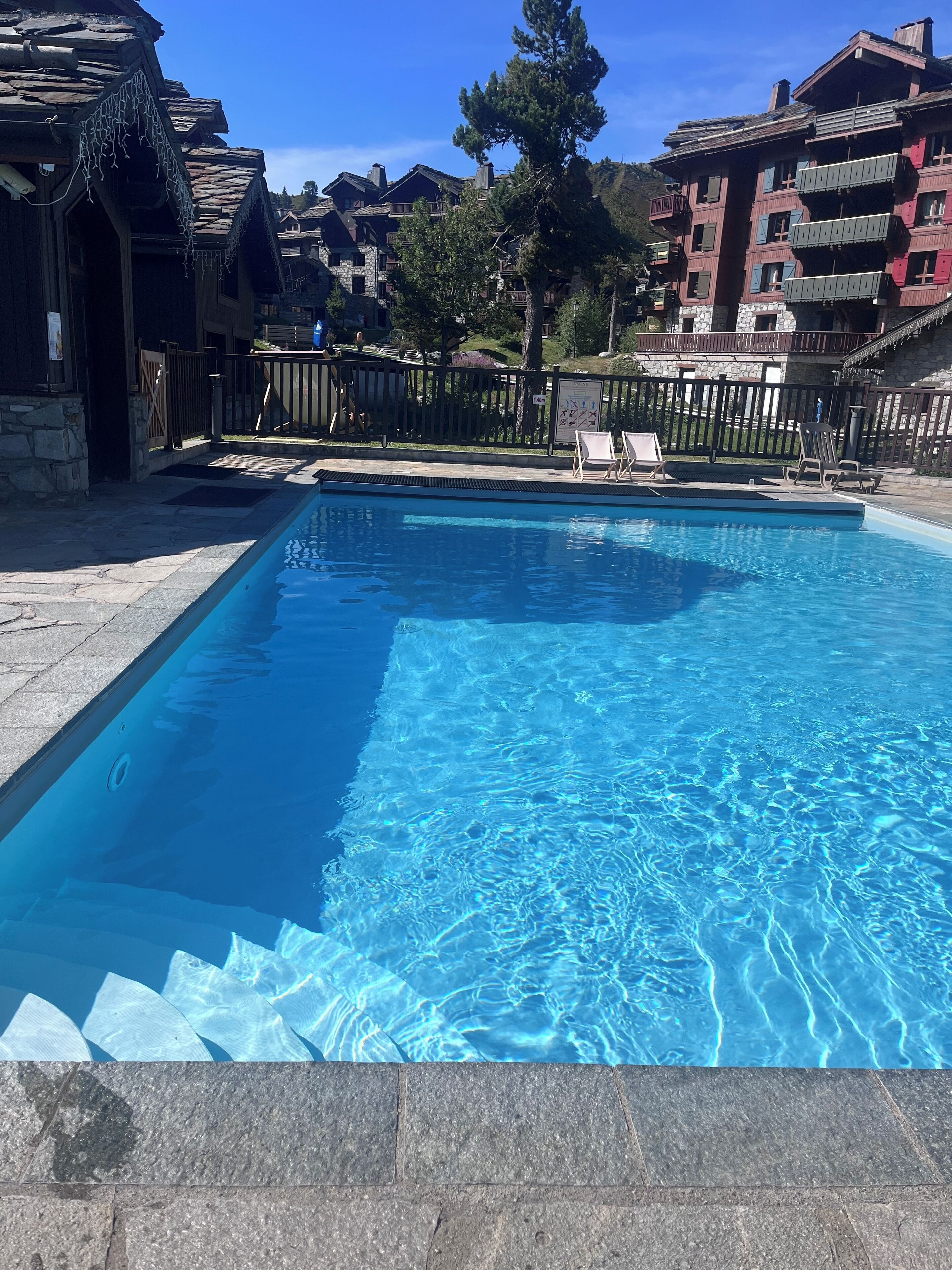 Une piscine à l’eau d’un bleu cristallin, entourée de carreaux de pierre.