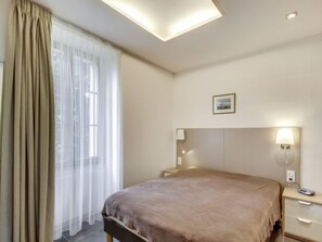 Relax in a spacious room with a large bed, bedside tables, and a window with sheer curtains.