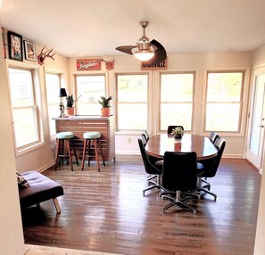 A dining area with a round table, black chairs, and a ceiling fan. There are potted plants on the windowsill and a bench in the corner. - Comfortable Cottage Retreat 4 Bed/2 Bath - Close to Everything! (Nashville)