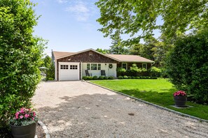 A single-story house with a garage, surrounded by a well-maintained lawn and trees.