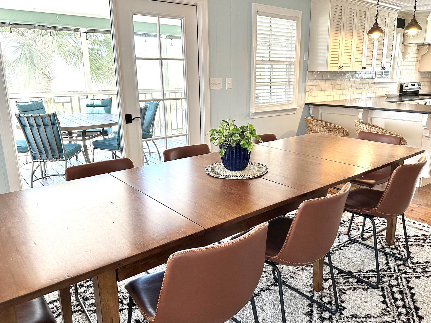 Uma sala de jantar com uma mesa de madeira, seis cadeiras e um vaso de planta.
