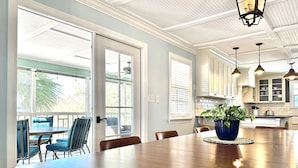 Uma sala de jantar espaçosa com uma mesa de madeira, cadeiras azuis e um vaso de planta.