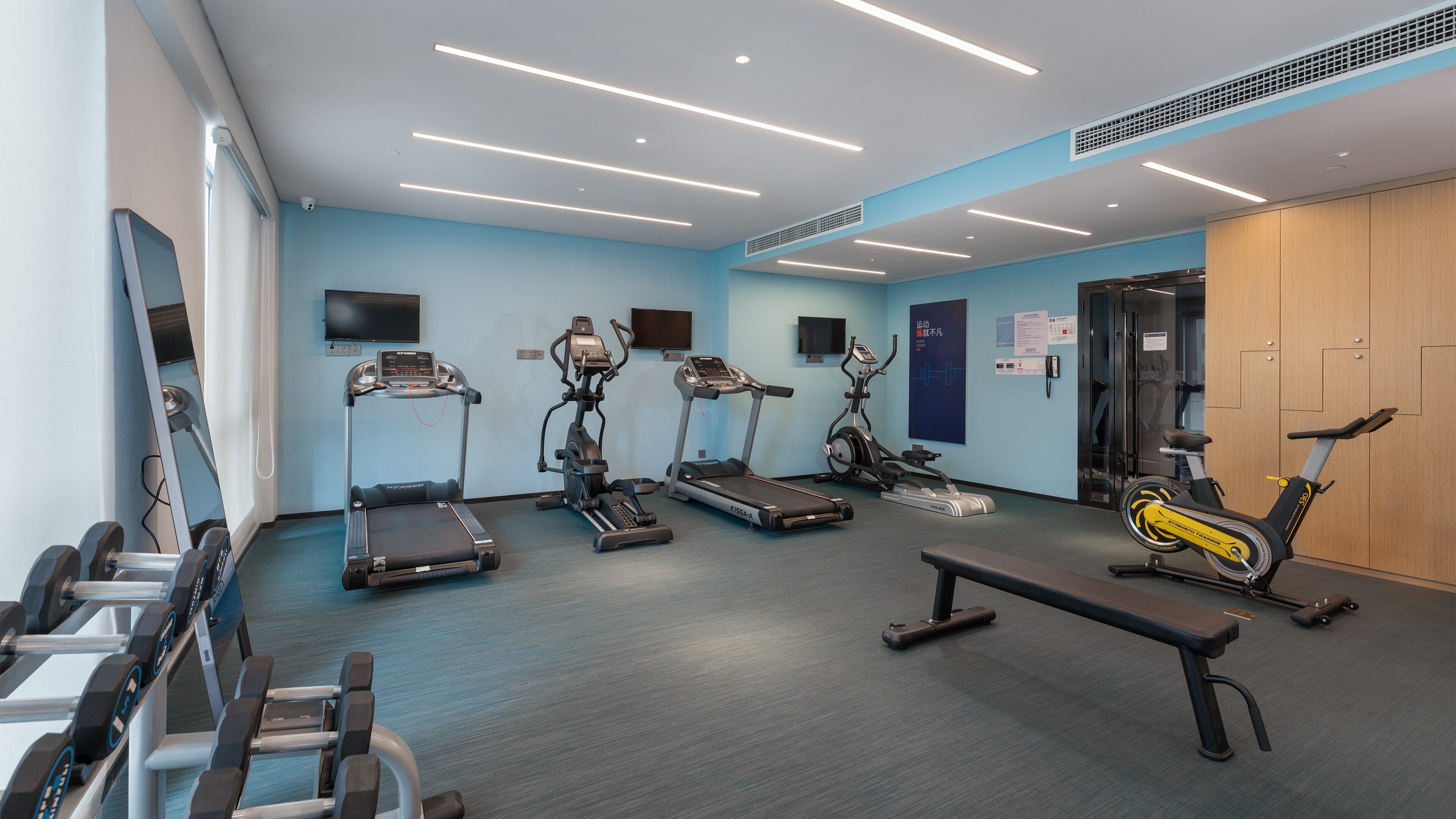 A gym with treadmills, stationary bikes, and dumbbells.