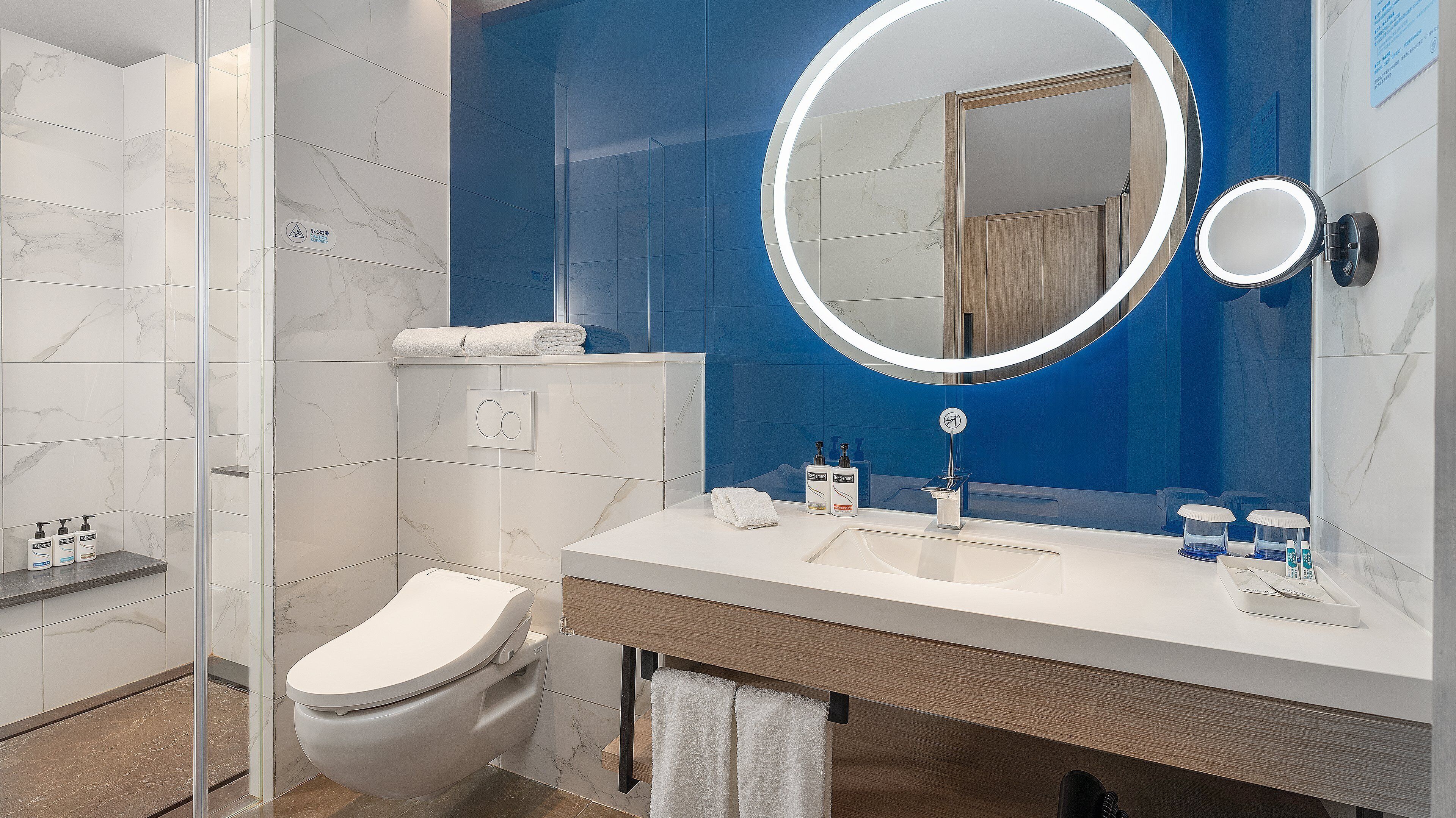 Egy modern fürőszoba, amelyben WC, mosdókagyló és zuhanyzó található.