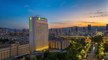 Un hotel grattacielo con insegne illuminate, circondato da un paesaggio urbano con edifici densi e un ponte sullo sfondo.