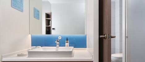 A modern bathroom with a white sink, a blue-tiled backsplash, and a wooden vanity.