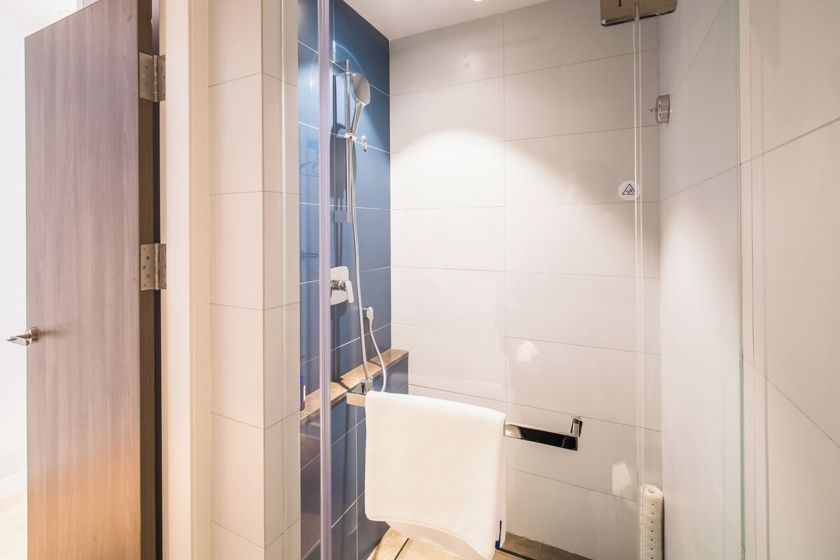 Un bagno moderno con box doccia in vetro, porta in legno e water bianco.