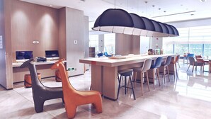 Un moderno hall de hotel con un mostrador de recepción alargado, asientos cómodos y ventanas amplias que ofrecen vistas a la ciudad.