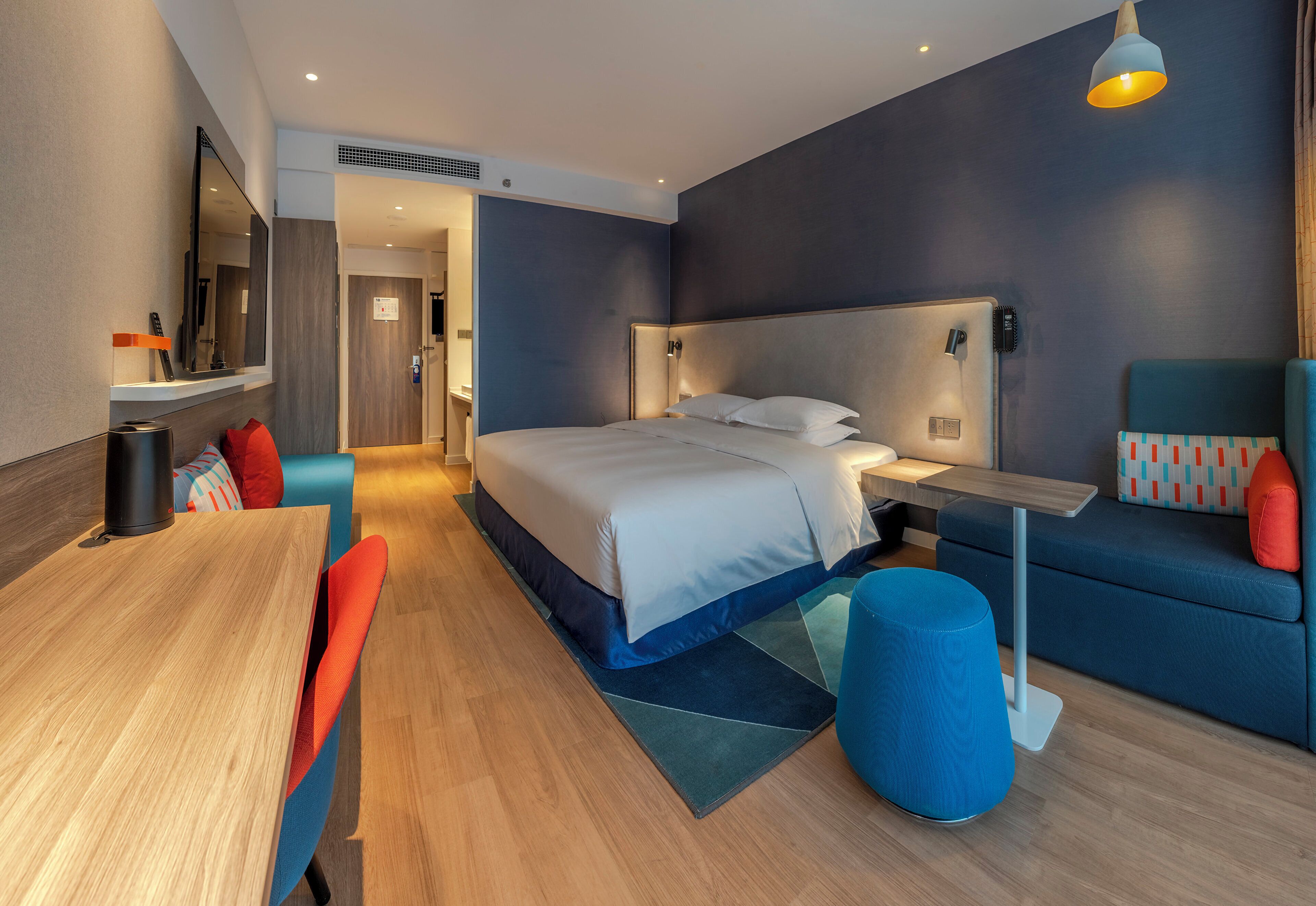 Una habitación de hotel moderna con cama, mesita de noche y zona de estar.