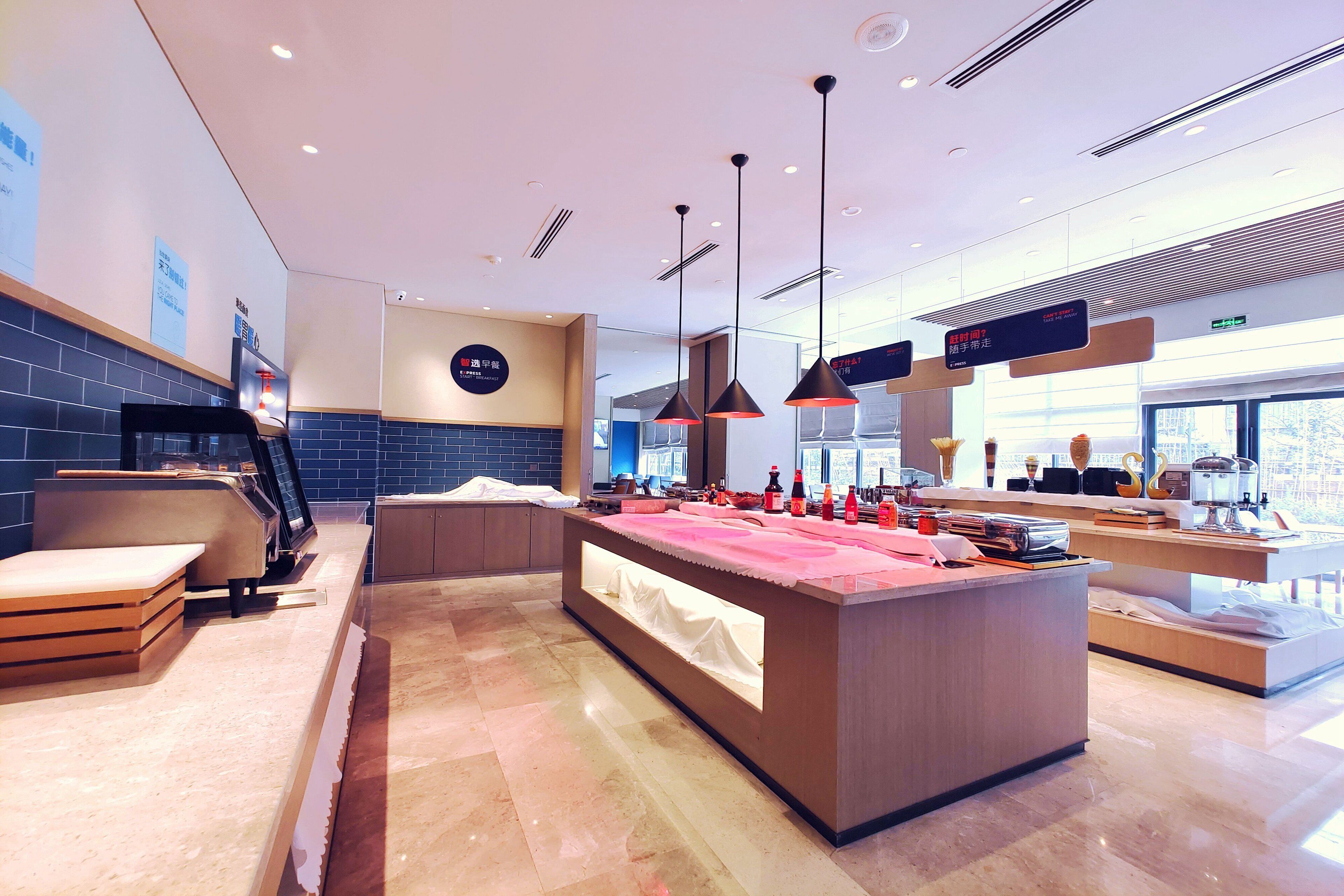 A modern breakfast area with a central island, seating, and a view of the city.