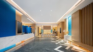 Un moderno vestíbulo de hotel con una recepción, zona de estar y un muro decorativo con diseños circulares.