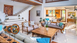 A spacious living area with a high ceiling, a wooden staircase, and a view of the kitchen. - Villa Rusa Biru - Peaceful Ricefield Views in Central Canggu (Kecamatan Kuta Utara)
