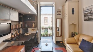 Un espacio habitable compacto con escritorio, computadora, estantería y sofá.