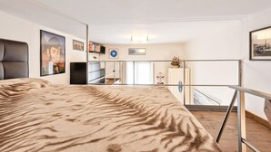 Un dormitorio con una cama grande, un escritorio, una silla, una estantería y un ventanal con vistas al exterior.