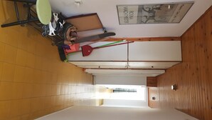 A narrow hallway with a tiled floor, a ceiling fan, a broom, and a mop leaning against the wall. - Specious room next to the beach (Tel Aviv-Yafo)