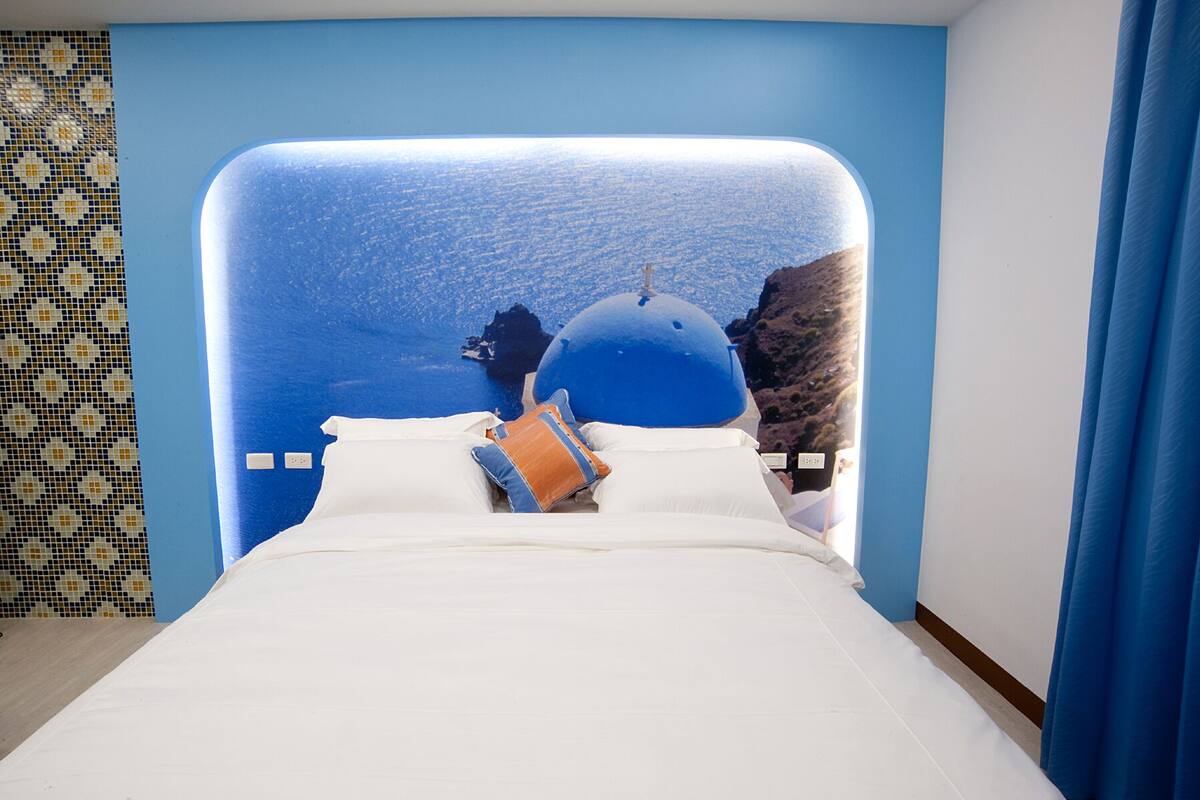 A hotel room with a large bed, a view of a blue dome and landscape, and a patterned wall.