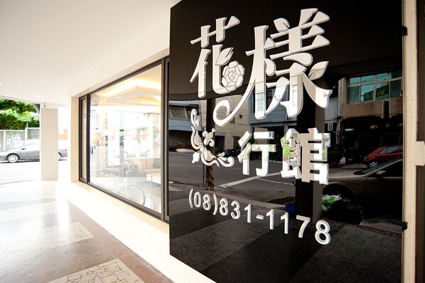 A hotel entrance with a large glass window and a sign with Chinese characters and a phone number. - Flower Style B&B (Donggang)