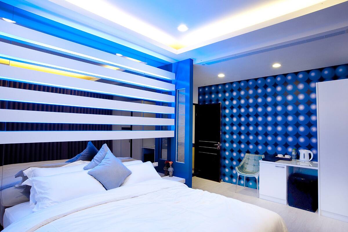 A modern bedroom with a bed, bedside tables, and a desk with a chair.