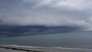 Ein Strand mit Blick auf den Ozean und einem bewölkten Himmel.